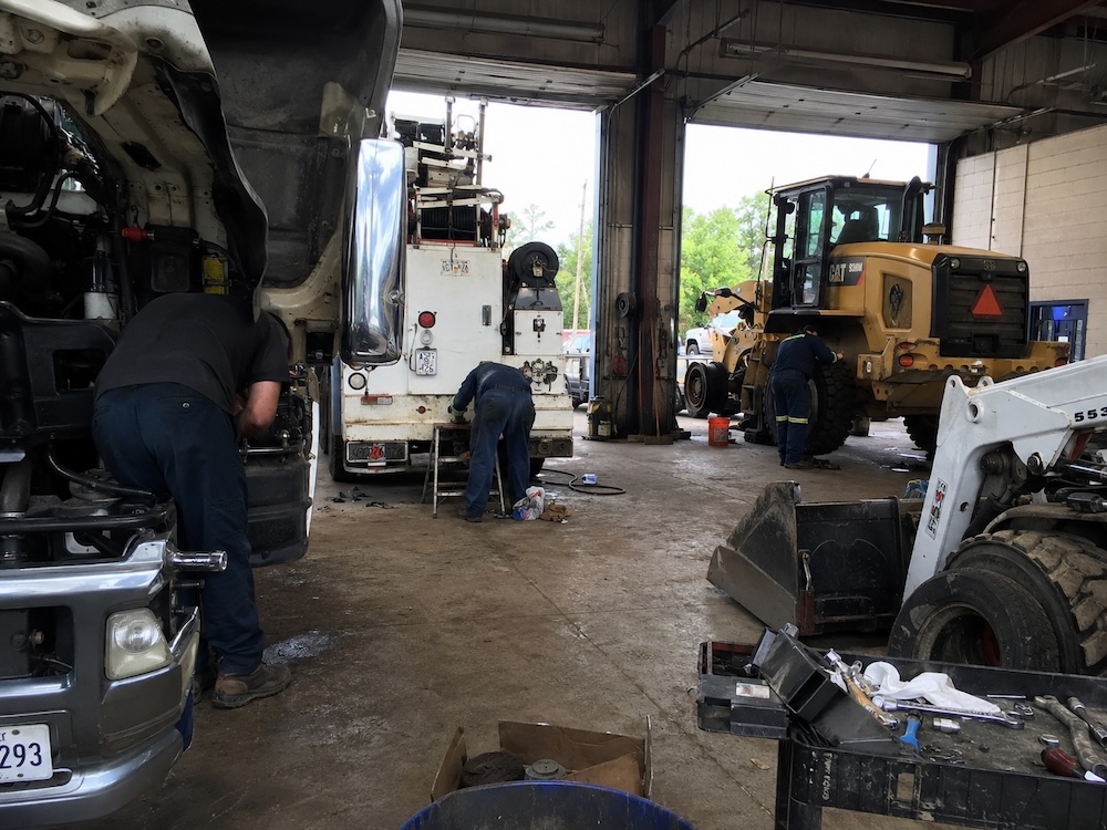 Construction fleet vehicles in a maintenance garage bay during scheduled service