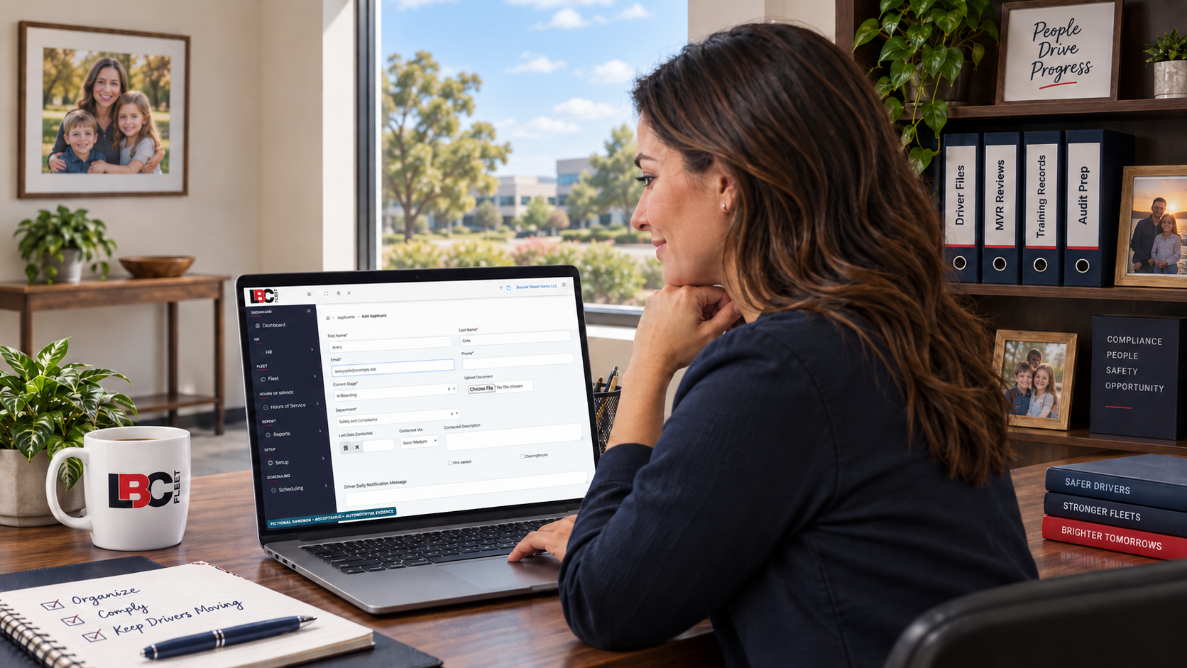 Fleet compliance professional reviewing the LBC Fleet Add Applicant screen in a fictional sandbox; the office includes labeled Driver Files, MVR Reviews, Training Records, and Audit Prep binders.